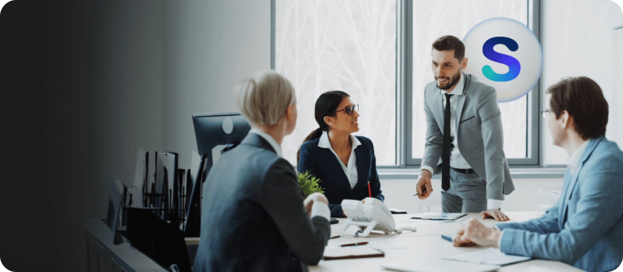 A team of real-estate professionals meeting around a conference table by a sunlit window.